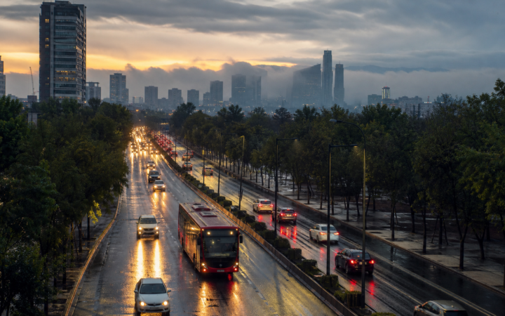 Avenida de Ciudad de México con tráfico matutino y pavimento mojado bajo cielo nublado