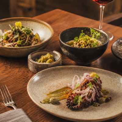 Platillos mexicanos contemporáneos y copas de vino en una mesa de experiencia gastronómica.