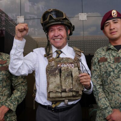 Ricardo Monreal porta chaleco y casco tácticos junto a dos militares durante una exhibición.