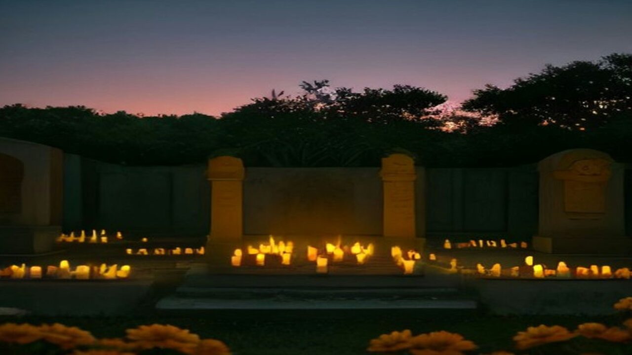 Panteón iluminado con velas y flores de cempasúchil al anochecer durante el Día de Muertos