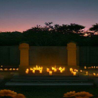Panteón iluminado con velas y flores de cempasúchil al anochecer durante el Día de Muertos