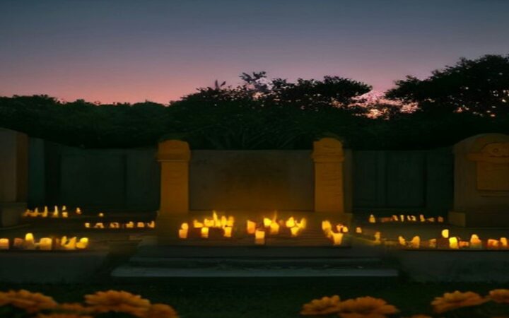 Panteón iluminado con velas y flores de cempasúchil al anochecer durante el Día de Muertos